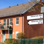 Ett rött hus i bakgrunden och adresskyltar i förgrunden.