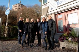 En grupp på sex kvinnor står utomhus bredvid varandra och ler mot kameran.