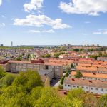 Utsikten från högsta våningen. Hustak och träd i solljus.