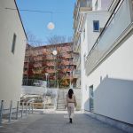 En kvinna går iväg från kameran. Hyreshus runt omkring.