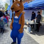 Reture, som är Bostadsbolagets maskot, är med på Tuvedagen. I bakgrunden står två av Bostadsbolagets medarbetare i ett blått tält.