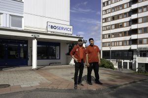 Två män tittar in i kameran och ler. De står utomhus på Friskväderstorget.